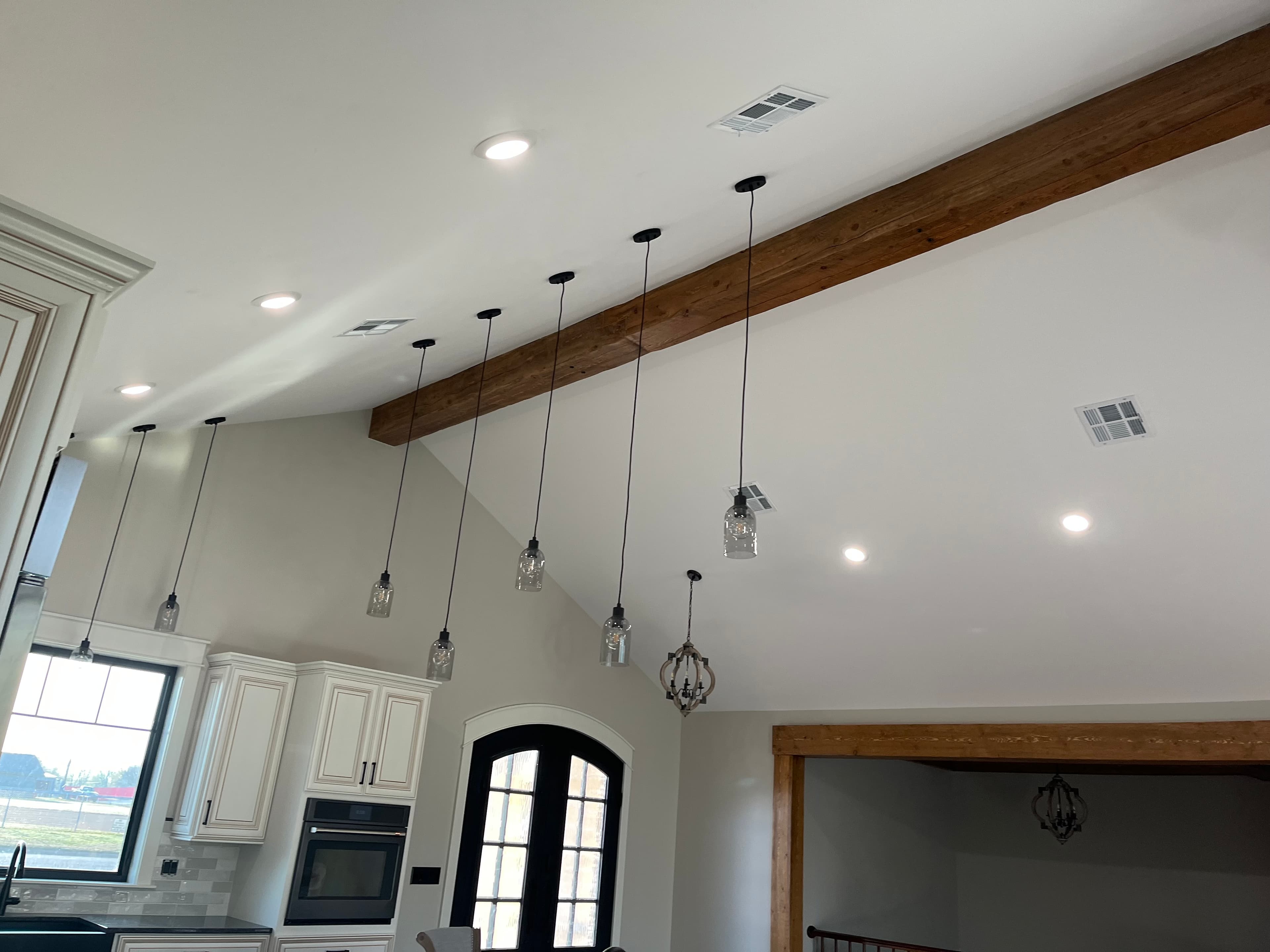 Vaulted ceiling with exposed wooden beams and multiple hanging glass jar pendant light fixtures.